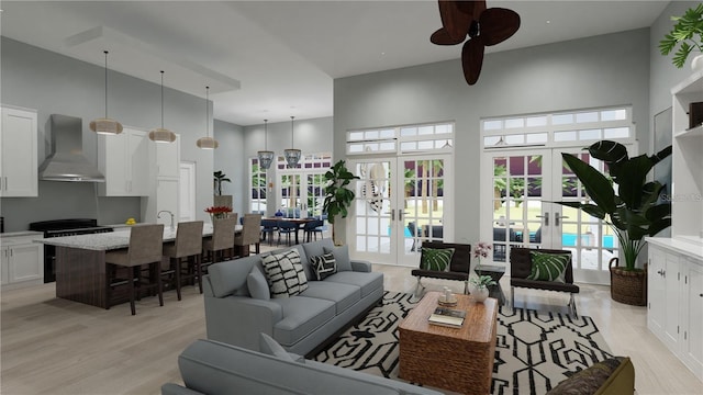 living room with a towering ceiling, light hardwood / wood-style flooring, and french doors