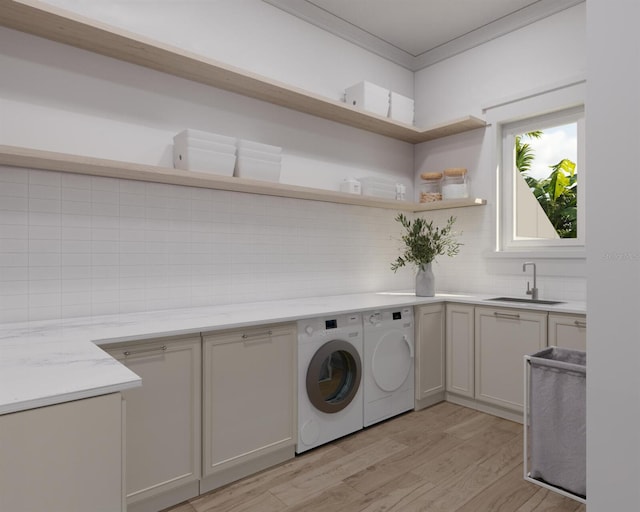 clothes washing area with light hardwood / wood-style flooring, cabinets, washer and clothes dryer, and sink