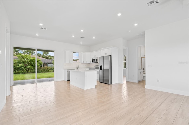 kitchen featuring light hardwood / wood-style floors, a center island, sink, white cabinets, and appliances with stainless steel finishes