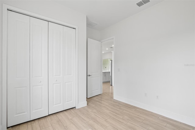 unfurnished bedroom with light hardwood / wood-style floors and a closet