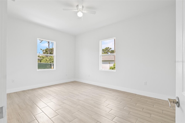 empty room featuring a wealth of natural light, ceiling fan, and light wood-type flooring