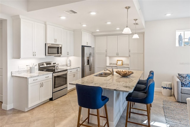 kitchen with appliances with stainless steel finishes, decorative light fixtures, sink, and white cabinets