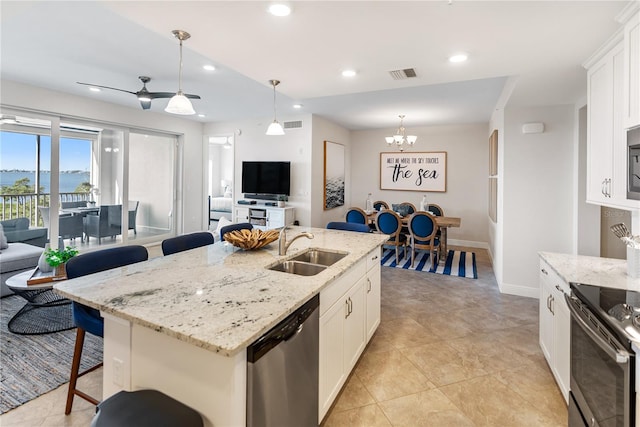 kitchen with stainless steel appliances, sink, a kitchen island with sink, and decorative light fixtures