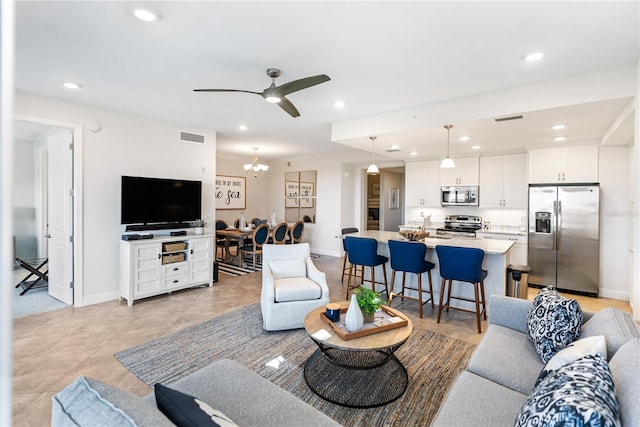 living room featuring ceiling fan with notable chandelier