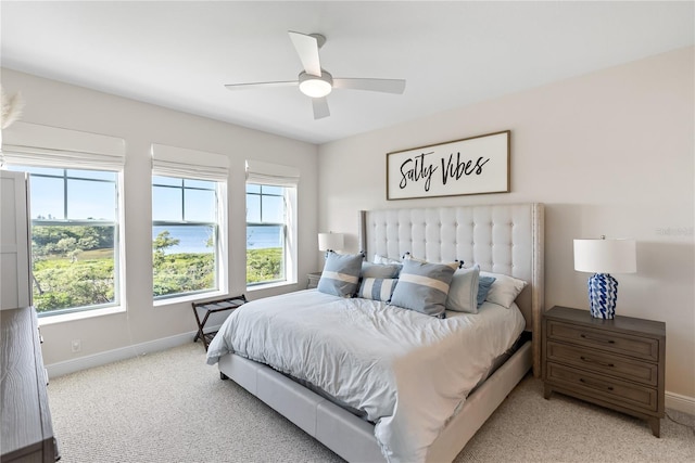 carpeted bedroom with multiple windows, a water view, and ceiling fan