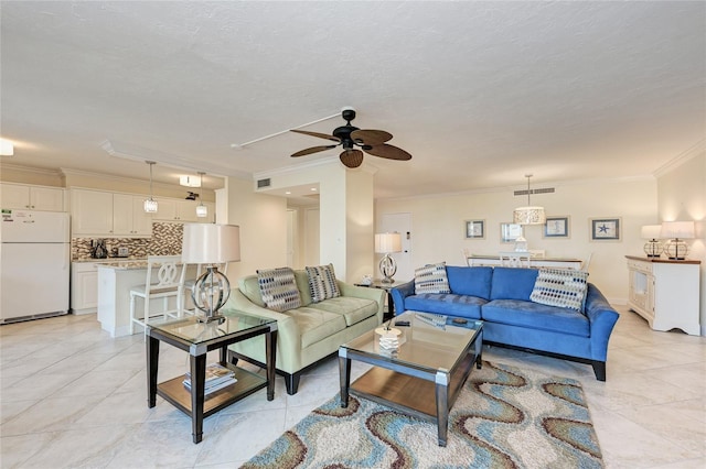 living area featuring a textured ceiling, ceiling fan, ornamental molding, and visible vents