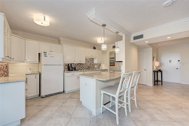 kitchen with light stone counters, visible vents, backsplash, freestanding refrigerator, and a peninsula