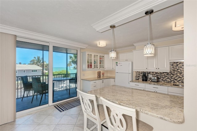 kitchen with crown molding, white cabinets, freestanding refrigerator, and a kitchen breakfast bar