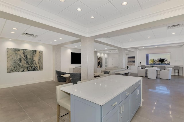 kitchen with light stone counters, tile patterned flooring, a kitchen island, open floor plan, and crown molding