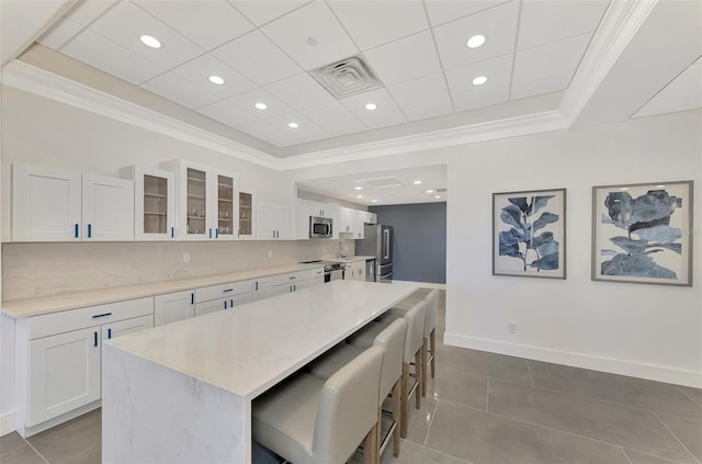 kitchen with stainless steel appliances, visible vents, a kitchen bar, glass insert cabinets, and crown molding