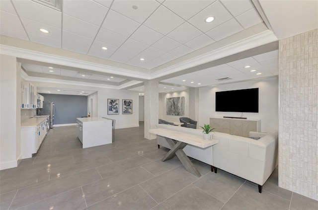 tiled living room featuring recessed lighting, a sink, baseboards, a raised ceiling, and crown molding