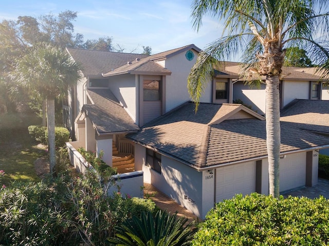 1654 Starling Dr Unit 201, Sarasota, FL 34231 - view of front of home featuring an attached garage, a shingled roof, and stucco siding