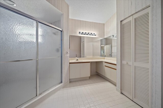 1654 Starling Dr Unit 201, Sarasota, FL 34231 - bathroom with a textured ceiling, vanity, a closet, a shower stall, and tile patterned floors