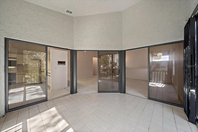 1654 Starling Dr Unit 201, Sarasota, FL 34231 - tiled empty room with visible vents, a textured wall, and a high ceiling