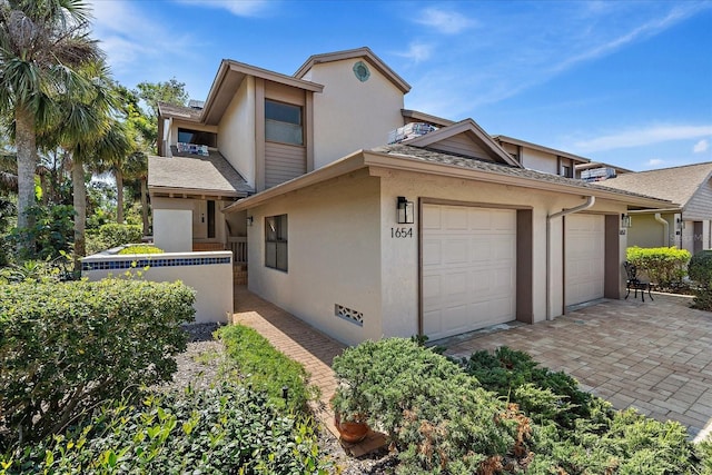 1654 Starling Dr Unit 201, Sarasota, FL 34231 - view of front of property featuring a shingled roof, decorative driveway, an attached garage, and stucco siding
