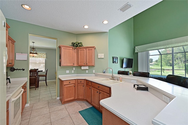 kitchen with sink, light tile patterned floors, a textured ceiling, decorative light fixtures, and range