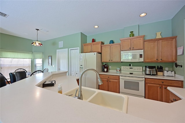 kitchen with pendant lighting, sink, white appliances, and a textured ceiling