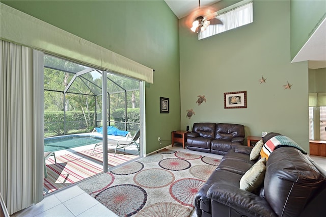 living room with tile patterned floors, ceiling fan, and a towering ceiling