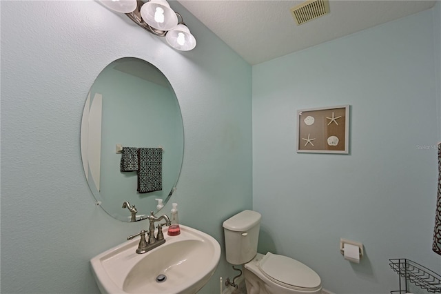 bathroom featuring a textured ceiling, toilet, and sink