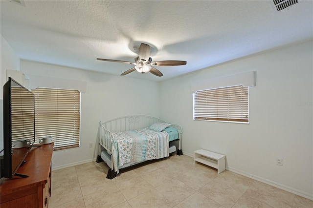 bedroom with light tile patterned floors, a textured ceiling, and ceiling fan