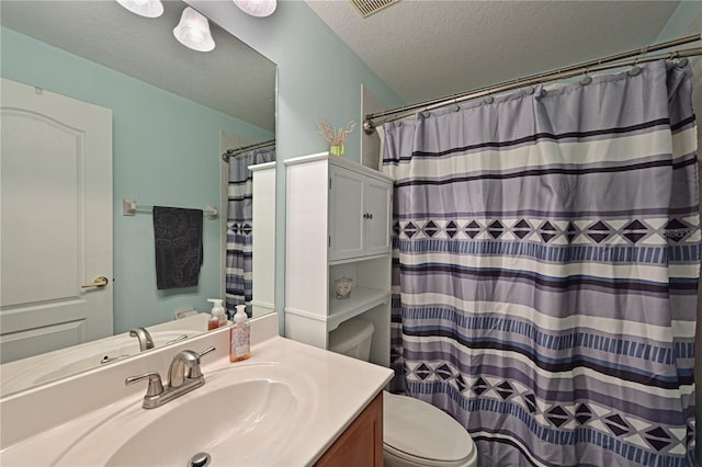 bathroom with a shower with curtain, vanity, a textured ceiling, and toilet