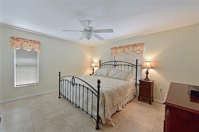 bedroom with ceiling fan, light tile patterned floors, and a textured ceiling