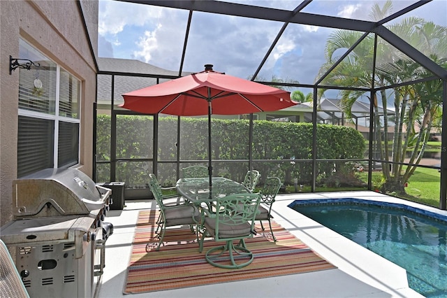 view of pool with grilling area, a patio, and glass enclosure