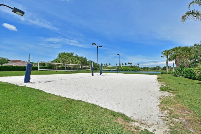 view of home's community with volleyball court, a yard, and a water view