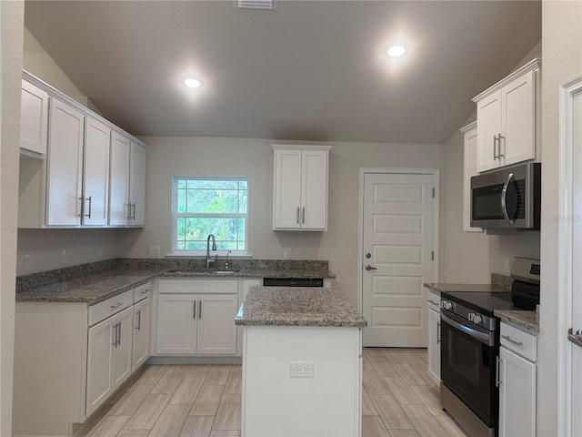 kitchen featuring appliances with stainless steel finishes, lofted ceiling, and white cabinets