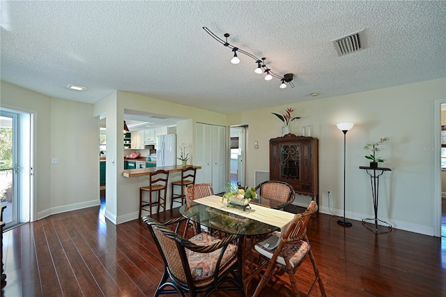 dining room with visible vents, baseboards, a textured ceiling, and wood finished floors