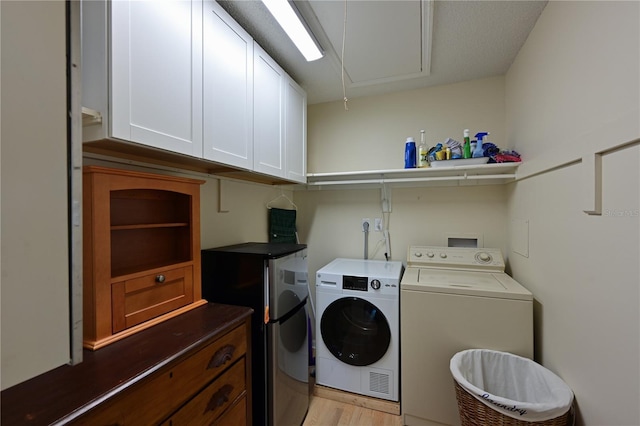 laundry area with attic access, cabinet space, light wood-style floors, and washing machine and clothes dryer