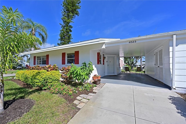 view of front of home featuring a carport, stucco siding, and driveway