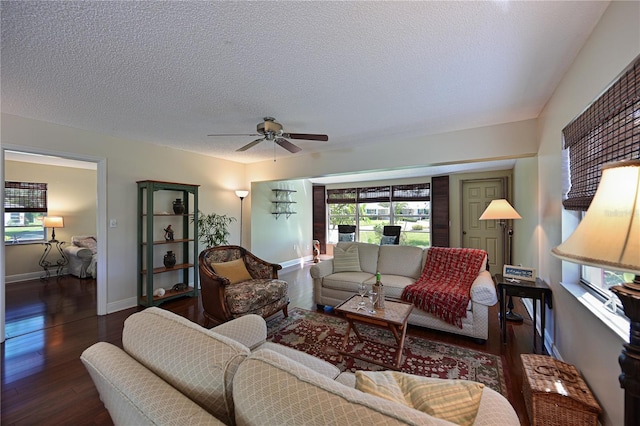 living room with ceiling fan, a textured ceiling, baseboards, and wood finished floors