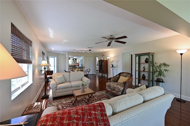 living area with dark wood-style floors, baseboards, ceiling fan, rail lighting, and a textured ceiling