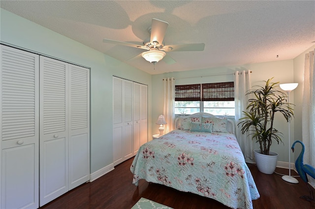 bedroom featuring dark wood finished floors, a textured ceiling, two closets, and a ceiling fan