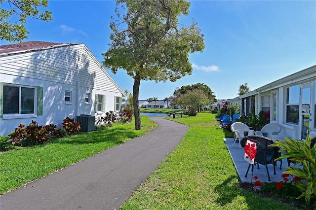 view of yard featuring a residential view, central AC unit, and a patio