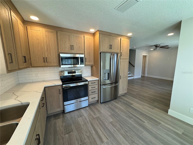 kitchen featuring ceiling fan, dark wood-type flooring, appliances with stainless steel finishes, backsplash, and sink