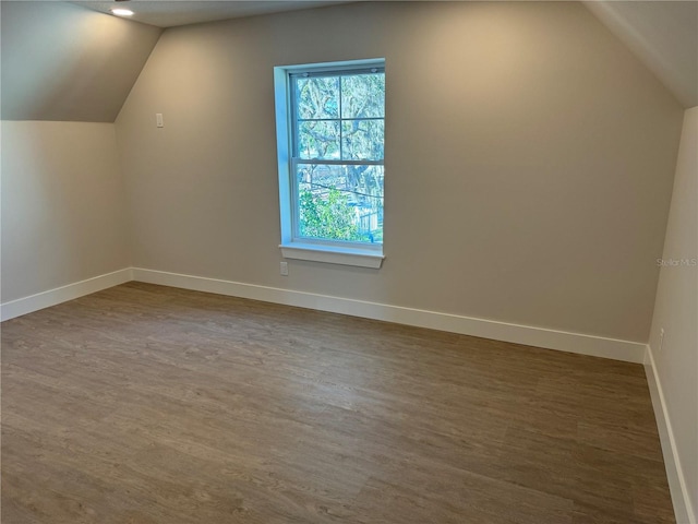 bonus room featuring vaulted ceiling and dark wood-type flooring