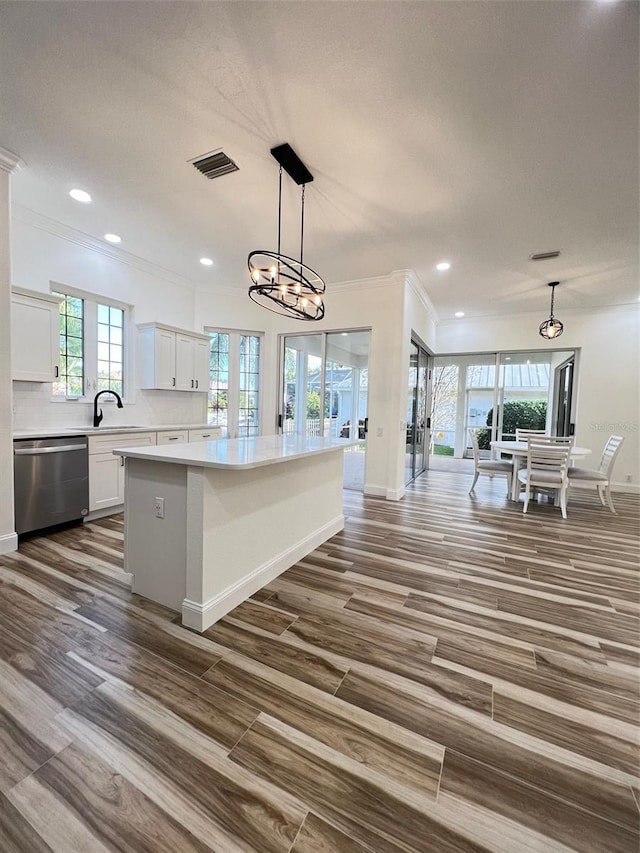 kitchen with dishwasher, a center island, an inviting chandelier, white cabinetry, and hanging light fixtures