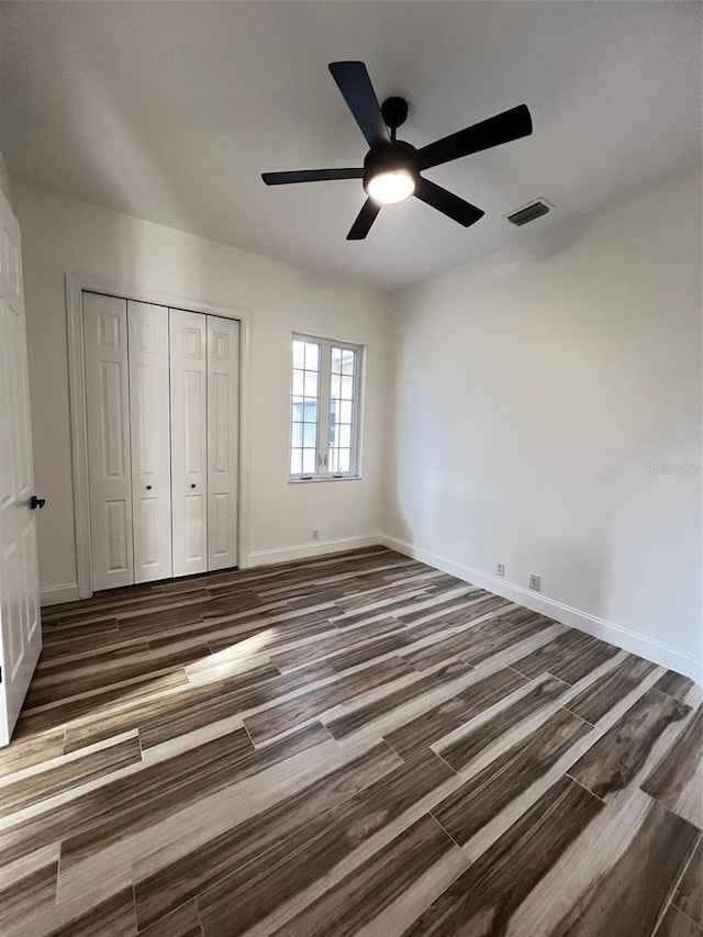 unfurnished bedroom featuring ceiling fan, dark wood-type flooring, and a closet