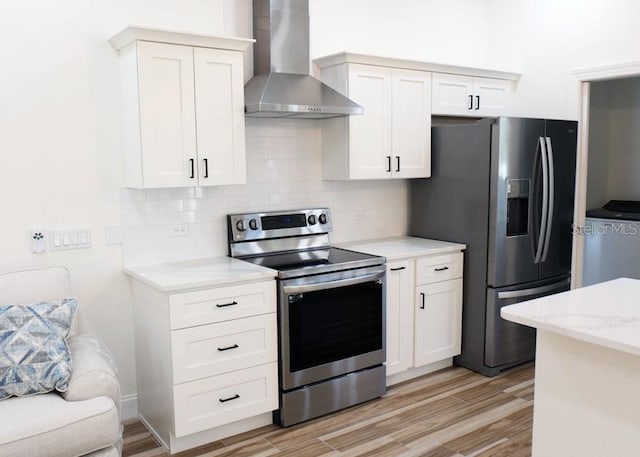 kitchen with stainless steel appliances, wall chimney exhaust hood, light hardwood / wood-style floors, and white cabinetry