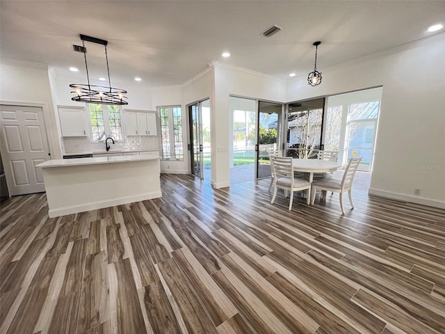 unfurnished dining area with dark wood-type flooring, sink, and crown molding