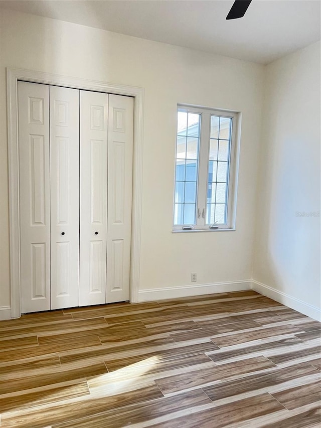 unfurnished bedroom with ceiling fan and a closet