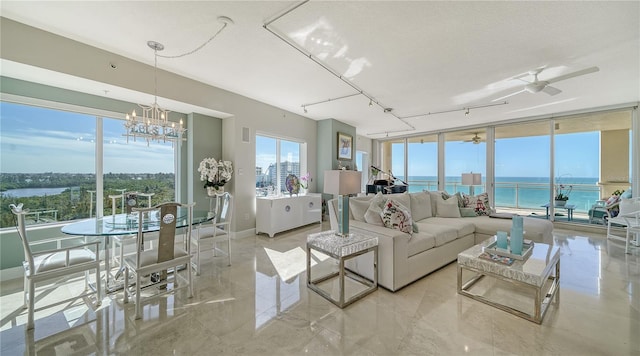 living room with a water view, ceiling fan with notable chandelier, track lighting, and light tile patterned floors