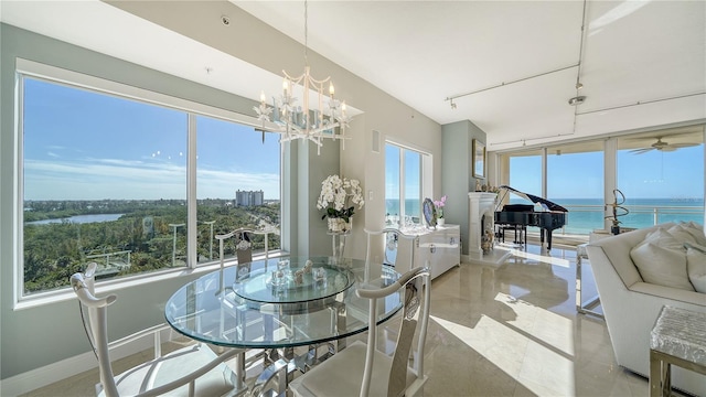 dining space with ceiling fan with notable chandelier and a water view