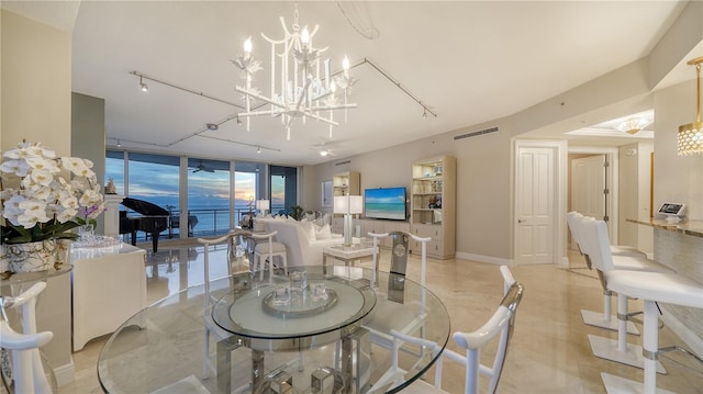 dining room with a wall of windows, track lighting, and an inviting chandelier