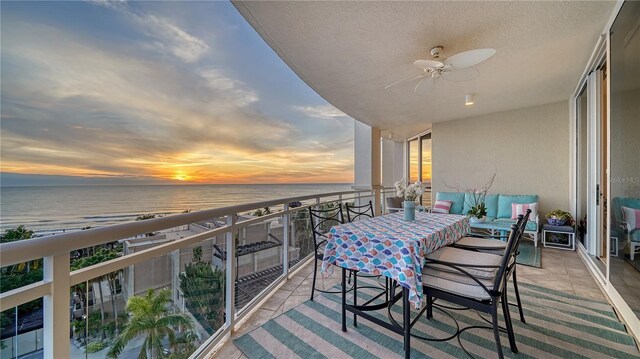 balcony at dusk featuring ceiling fan and a water view