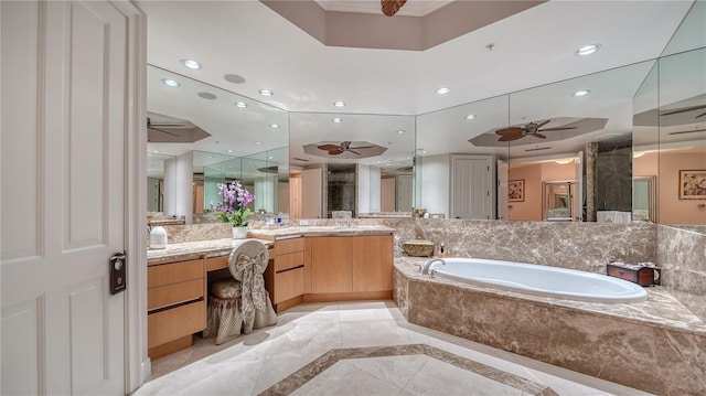 bathroom featuring tiled tub, ceiling fan, and vanity