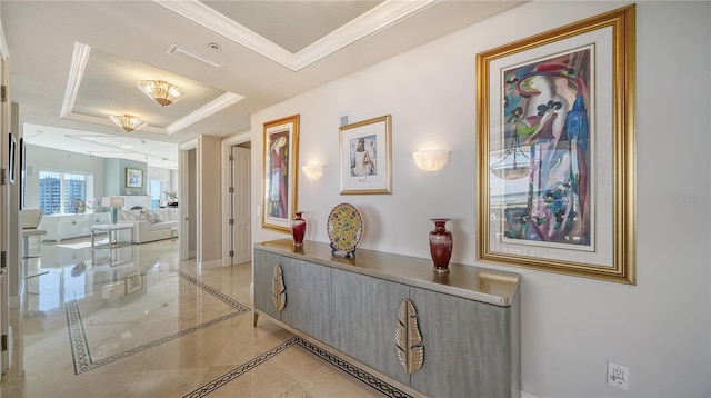 hallway with a tray ceiling and crown molding