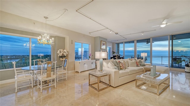 living room featuring ceiling fan with notable chandelier, a water view, and floor to ceiling windows